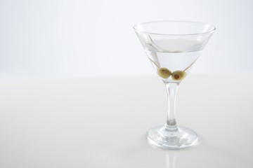 Cocktail martini with olives on table