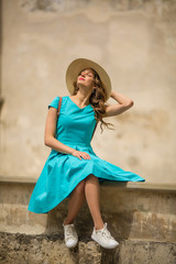 Tranquil traleving smiling woman sitting in ancient place, outdoor, summer in dress, hat