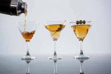 Cocktail poured in glass with olives on table