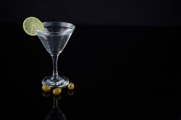 Cocktail martini with olives and lime on table