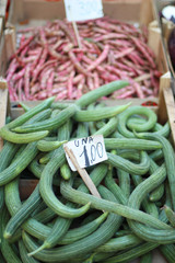Fruits of exotic cucumber and red beans in boxes on the market counter