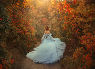 A young princess turns in a beautiful blue dress. The background is bright, golden autumn nature....