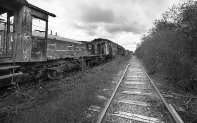 Hopeless post apocalyptic landscape. Cemetery of abandoned broken trains. Monochrome photo.