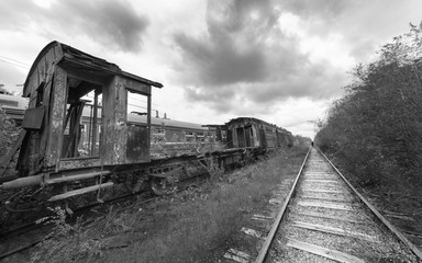 Fototapeta na wymiar Hopeless post apocalyptic landscape. Cemetery of abandoned broken trains. Monochrome photo.