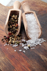 rough salt and mixed peppercorns on wooden shovels.