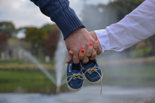 Parents Holding The Shoes Of Their Baby Boy