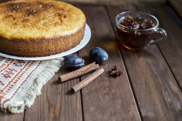 A cup of tea, pie, plums and spices.