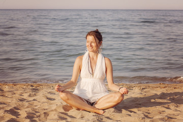 Fototapeta na wymiar Happy young woman meditating by the sea shore