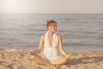 Happy young woman meditating by the sea shore