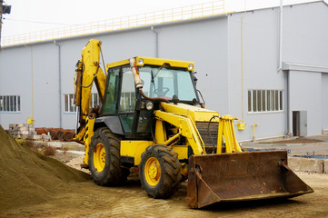 The concept of agronomy, a yellow tractor with a bucket demonstrates work