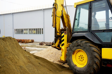 The concept of agronomy, a yellow tractor with a bucket demonstrates work