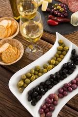 Close-up of marinated olives with bottle of wine and food