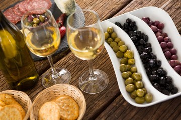 Close-up of marinated olives with bottle of wine and food
