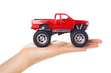 big metal red toy car offroad with monster wheels in hand isolated on white background © Sviatoslav Kovtun