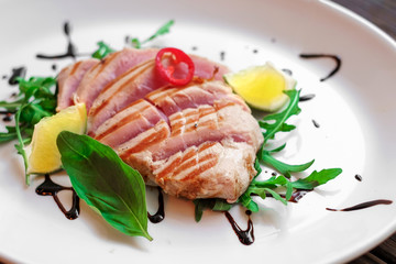 tuna fillet grilled on a white plate and wooden background