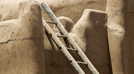 A Log Ladder Leans Against a Stucco Wall