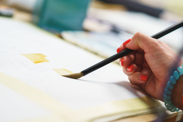 Artist makes the first brush strokes on a clean canvas while painting a watercolor painting.