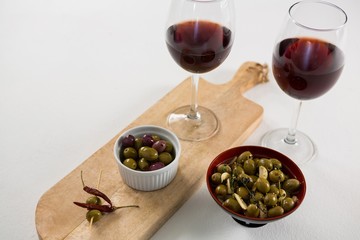Close-up of marinated olives with glasses of wine