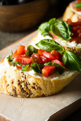 Tomato and cheese fresh made bruschetta. Italian tapas, antipasti with vegetables, herbs and oil on grilled ciabatta and baguette bread.