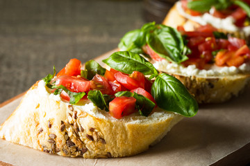 Tomato and cheese fresh made bruschetta. Italian tapas, antipasti with vegetables, herbs and oil on grilled ciabatta and baguette bread.
