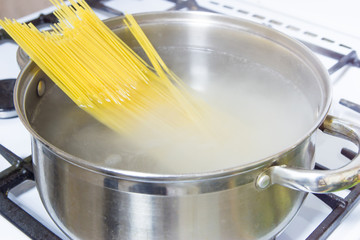 Spaghetti cooked in boiling water on a gas stove.