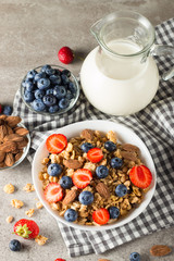 Healthy breakfast concept with oat flakes and fresh berries on rustic background. Food made of granola, muesli. Healthy banana smoothie with blackberries, muslie, strawberries, blueberries and honey.