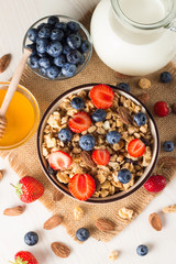 Healthy breakfast concept with oat flakes and fresh berries on rustic background. Food made of granola, muesli. Healthy banana smoothie with blackberries, muslie, strawberries, blueberries and honey.