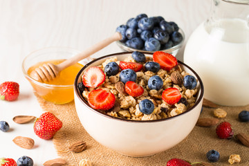 Healthy breakfast concept with oat flakes and fresh berries on rustic background. Food made of granola, muesli. Healthy banana smoothie with blackberries, muslie, strawberries, blueberries and honey.
