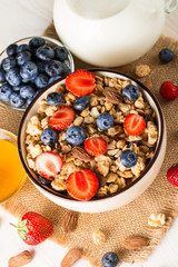Healthy breakfast concept with oat flakes and fresh berries on rustic background. Food made of granola, muesli. Healthy banana smoothie with blackberries, muslie, strawberries, blueberries and honey.