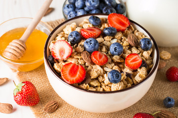Healthy breakfast concept with oat flakes and fresh berries on rustic background. Food made of granola, muesli. Healthy banana smoothie with blackberries, muslie, strawberries, blueberries and honey.