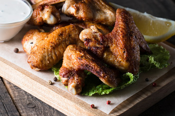Close-up photo of bbq chicken wings with fries and beer. Barbeques meat with sauces, ketchup, mayonnaise. Fast and junk food concept. 