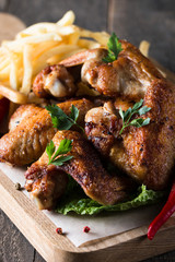 Close-up photo of bbq chicken wings with fries and beer. Barbeques meat with sauces, ketchup, mayonnaise. Fast and junk food concept. 