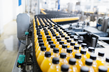 Bottling factory - Orange juice bottling line for processing and bottling juice into bottles. Selective focus. 