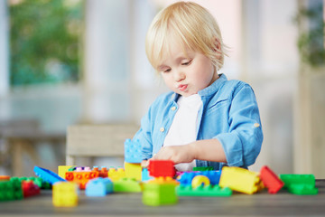 Little boy playing with colorful plastic construction blocks
