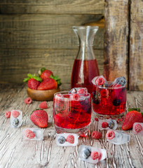 Summer berry lemonade with frozen berries on a wooden rustic table, selective focus