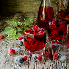 Summer berry lemonade with frozen berries on a wooden rustic table, selective focus