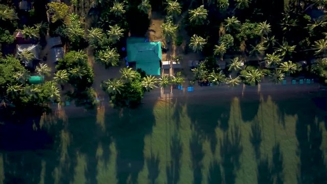 Looking straight down at the backpacker tourist accommodations on the beach, the camera moves to the right slowly at sunrise on Koh Tonsay.
