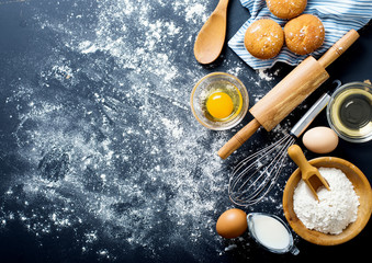 Baking ingredients. Bowl, eggs, flour, eggbeater, rolling pin and eggshells on black chalkboard...