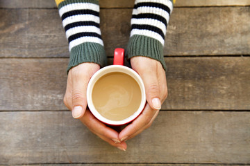 Woman hands holding hot coffee on wooden table