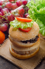 Hamburger with grilled pork and fresh vegetable on wooden table