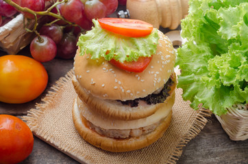 Hamburger with grilled pork and fresh vegetable on wooden table