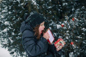 The girl opens a red box with a gift.