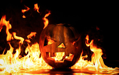 The concept of Halloween. The evil terrible pumpkin is burning in the hellish tongues of flame. Jack Lantern in the middle of the fire