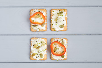 Tasty crackers with cream cheese, vegetables. Appetizers on grey table. Healthy snacks, top view, flat lay