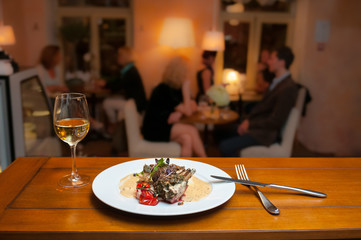 Lamb with potatoes and mushrooms sauce in the french restaurant and a wine glass.