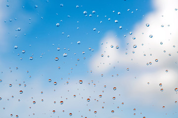water drops rain on glass on background of blue sky