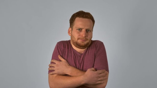 caucasian guy with red hair feels cold and chilly. handsome redheaded men wearing in casual t-shirt laughing looking at the camera. Portrait ginger young caucasian man on grey background