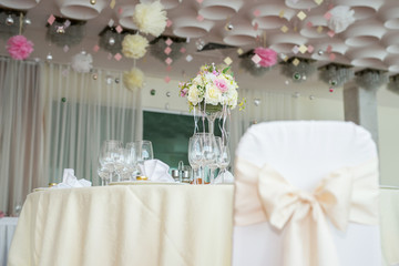 Beautiful wedding floral decoration on a table in a restaurant.White tablecloths, bright room.