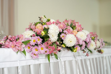 Beautiful wedding floral decoration on a table in a restaurant.White tablecloths, bright room.