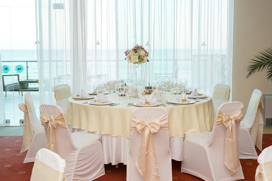 Beautiful wedding floral decoration on a table in a restaurant.White tablecloths, bright room.